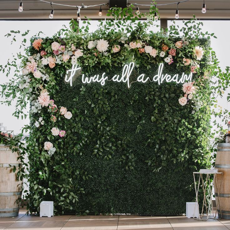 a wedding backdrop with flowers and greenery on the wall that says it was all a dream