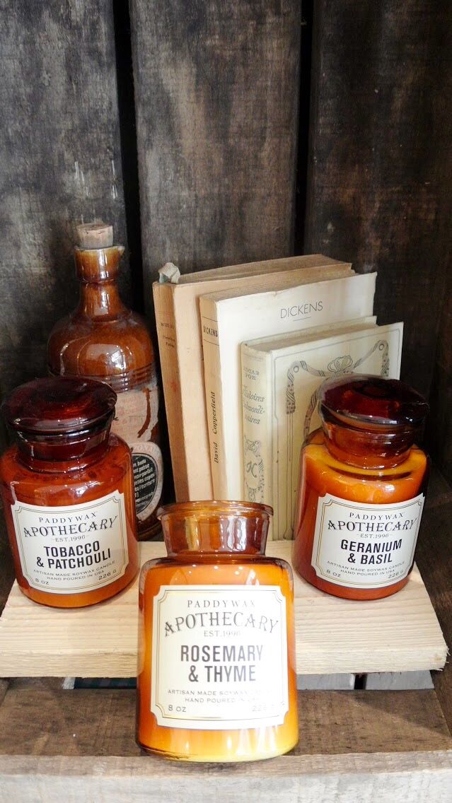three jars of honey sitting on top of a wooden shelf next to books and other items