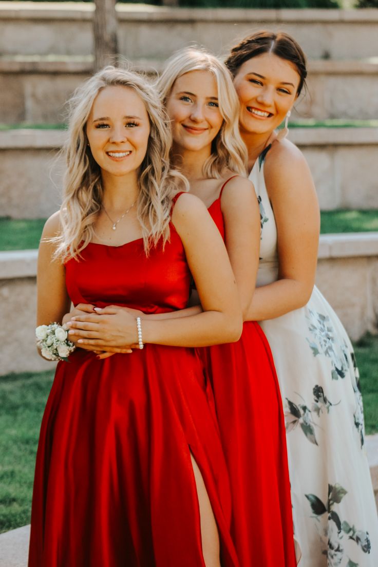 three women in red dresses standing next to each other with their arms around one another