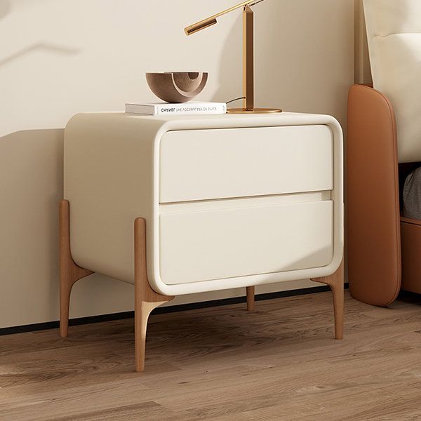 a white nightstand sitting next to a bed in a room with wooden floors and walls