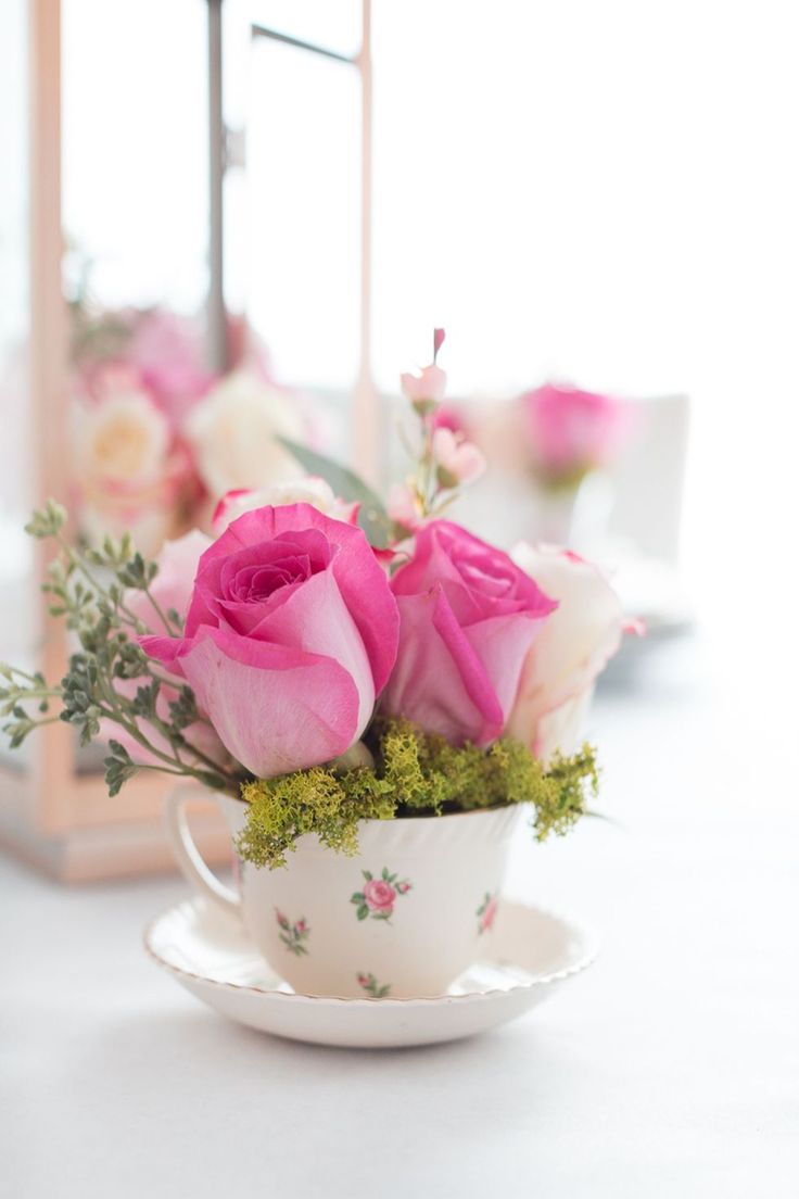 pink roses in a teacup on a table