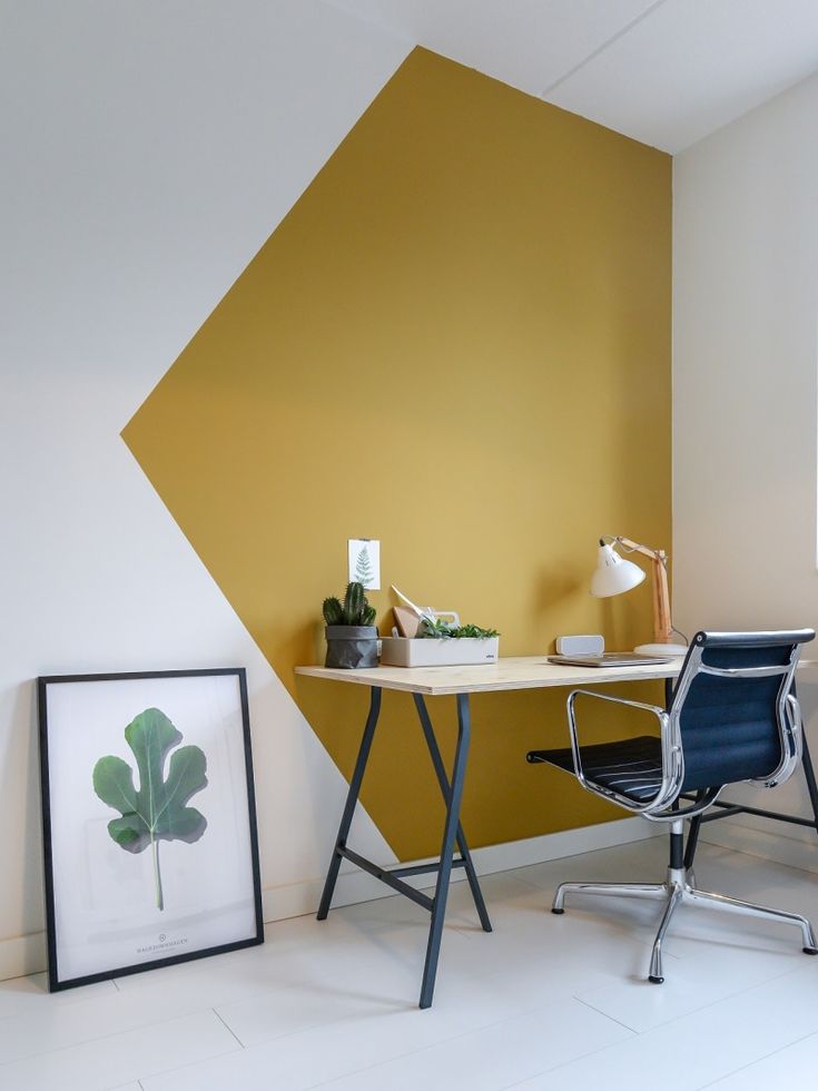 an office with a desk and chair in front of a wall painted yellow, white and black