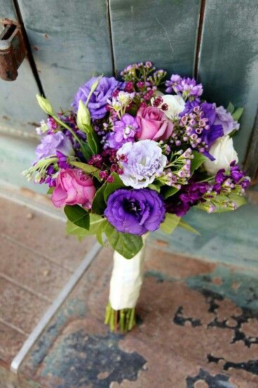 a bouquet of purple and white flowers sitting on top of a wooden chair next to a door