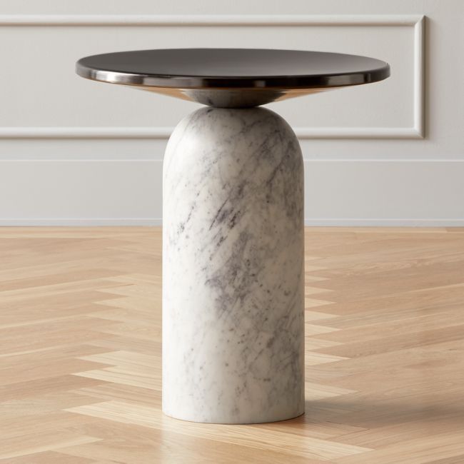a marble table with a black top on a wooden floor in front of a white wall
