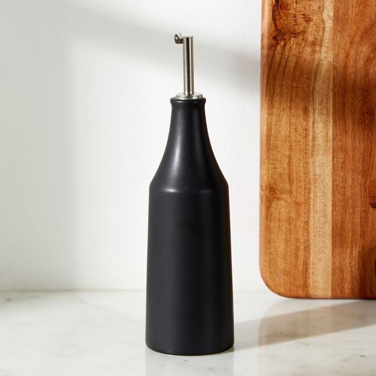 a black bottle sitting on top of a counter next to a cutting board