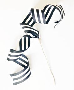 black and white striped streamers on a white background, one is tied to a string