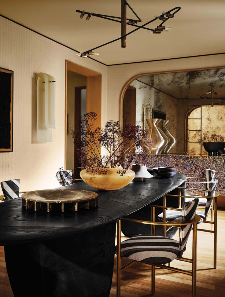 a dining room with black table cloth and gold vases on it's centerpiece