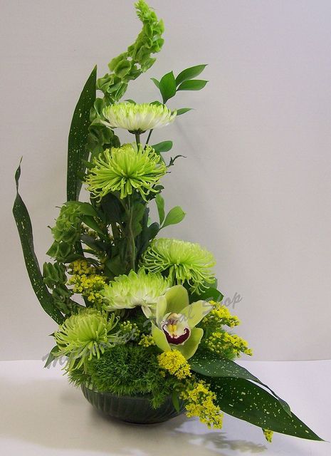 a vase filled with green flowers and greenery