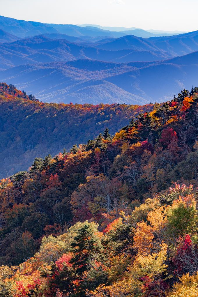 the mountains are covered in fall foliage and trees with orange, yellow, and red leaves