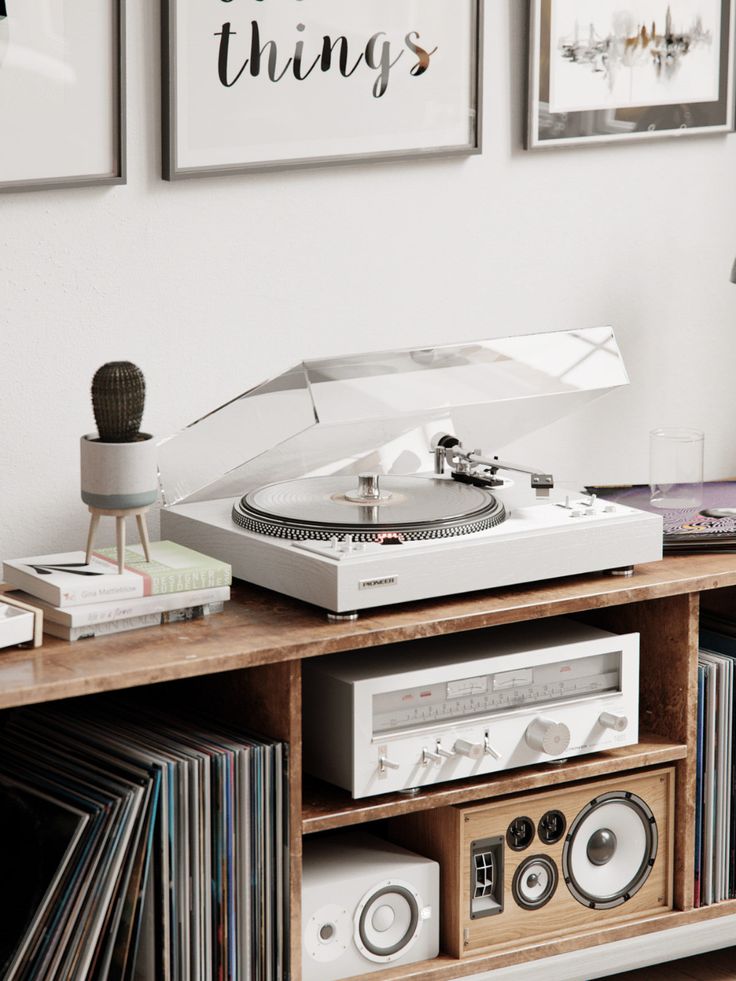 a record player sitting on top of a wooden shelf next to a wall with pictures above it