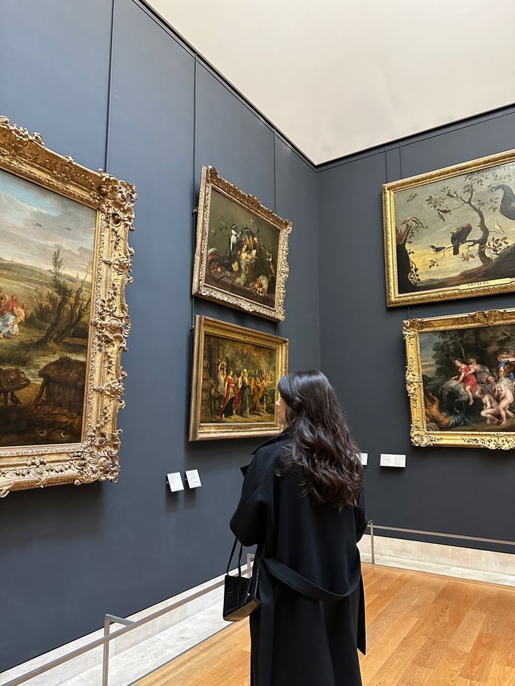 a woman is looking at paintings on the wall