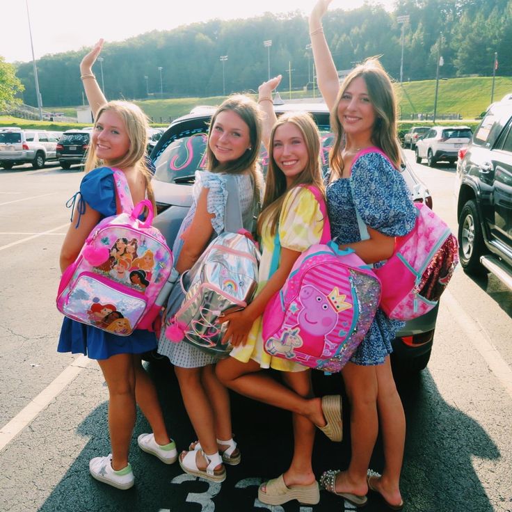 four girls are standing in the back of a car with backpacks on their shoulders