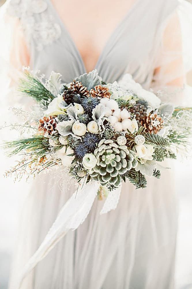 a woman holding a bouquet of flowers and pine cones on her wedding day, text reads happywedd com 25 chic winter wedding bouquets i hap