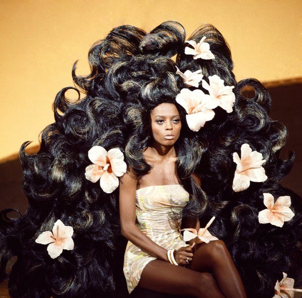 a woman sitting on top of a pile of black hair with flowers in her hair