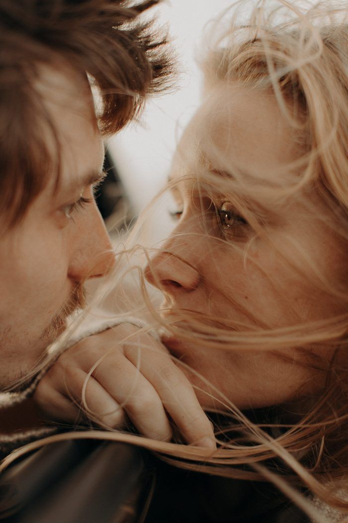 a man and woman kissing each other with long hair blowing in front of their faces