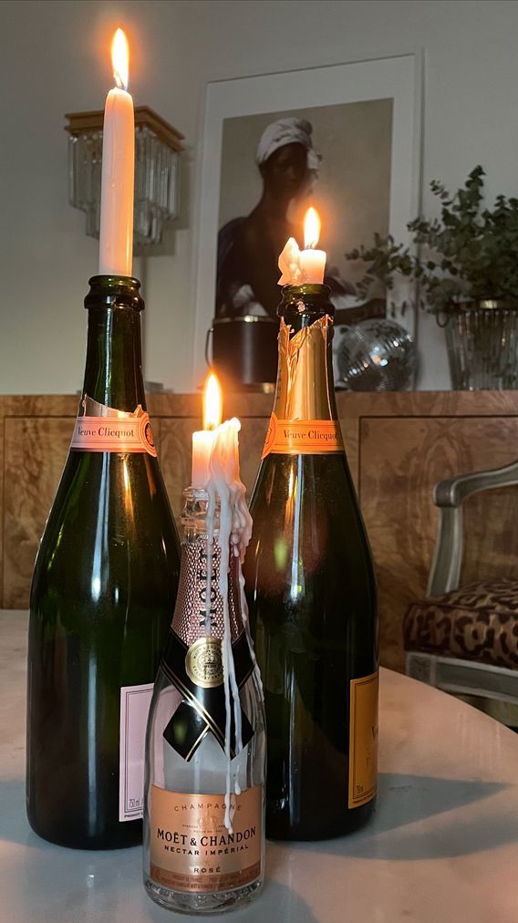 two champagne bottles with candles in them sitting on a table