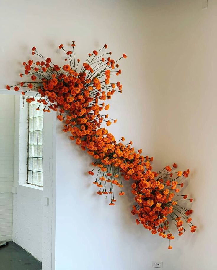 an arrangement of orange flowers is hanging on the wall