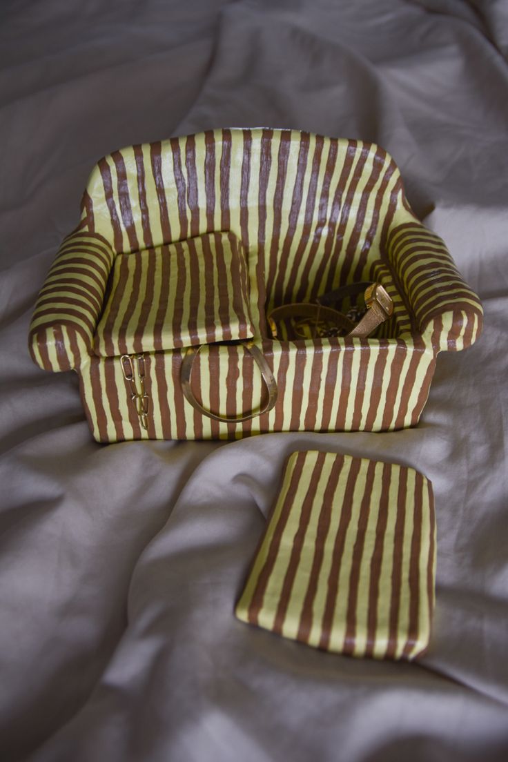 a brown and white striped bag sitting on top of a bed next to a pillow