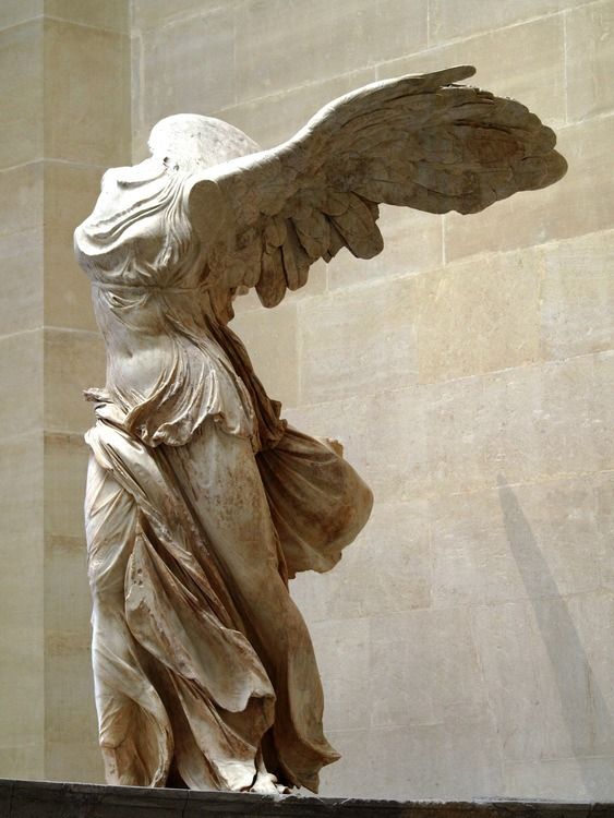 an angel statue with its wings spread out in front of a stone wall and ceiling