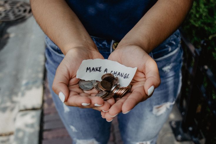 a person holding some coins with the words make a change written on them in their hands