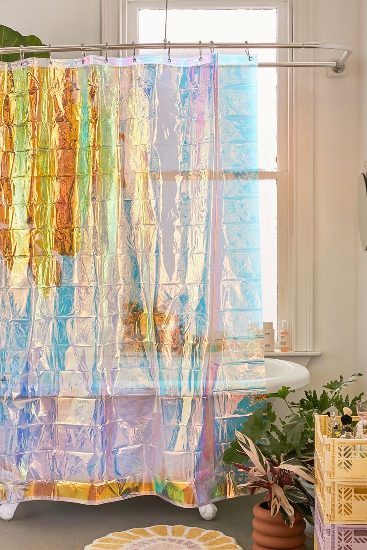 a colorful shower curtain in a bathroom next to a potted plant and window sill