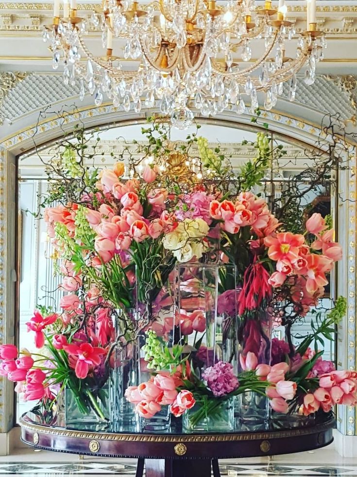 a table topped with lots of pink and white flowers next to a chandelier