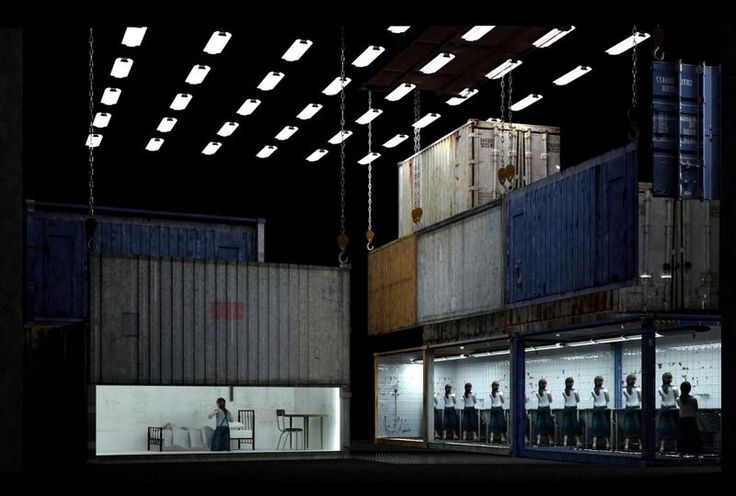 people are standing outside in front of some shipping containers at night with their backs turned to the camera