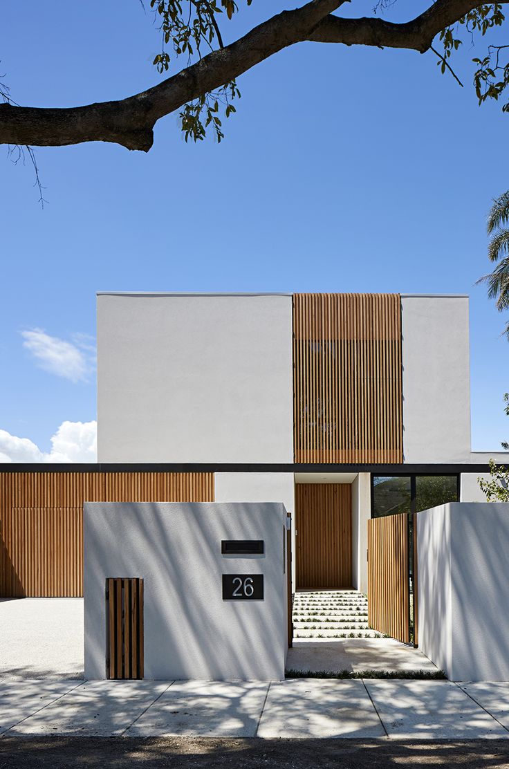 the entrance to a modern house with wooden slats on the wall and steps leading up to it