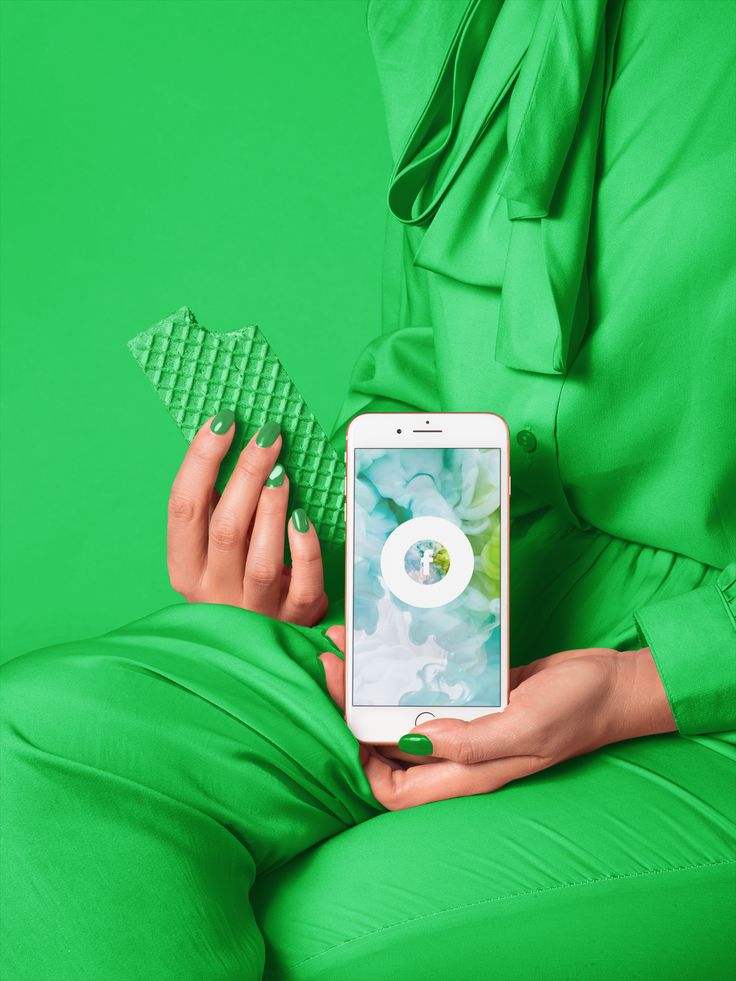 a woman in green pants is holding a cell phone with an app on the screen