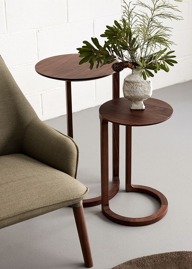 two small tables with plants in them sitting next to each other on the floor near a chair
