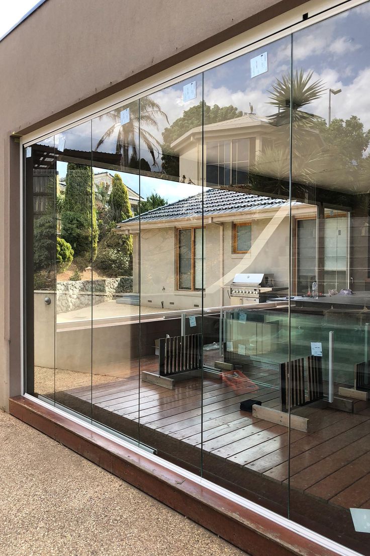 the reflection of a house in a glass window with chairs on the outside and an outdoor hot tub behind it