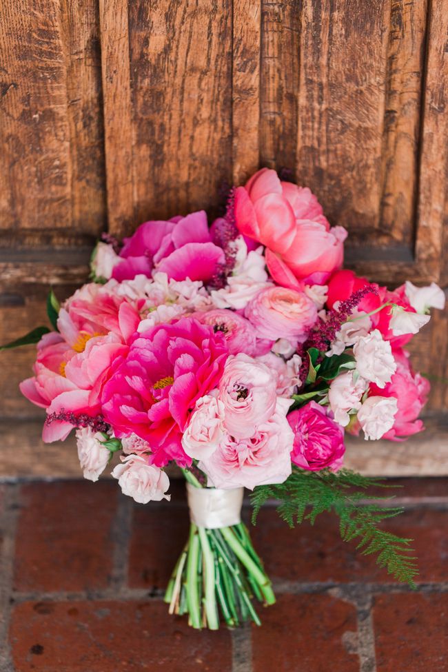 a bouquet of pink and white flowers sitting on top of a brick floor next to a wooden door