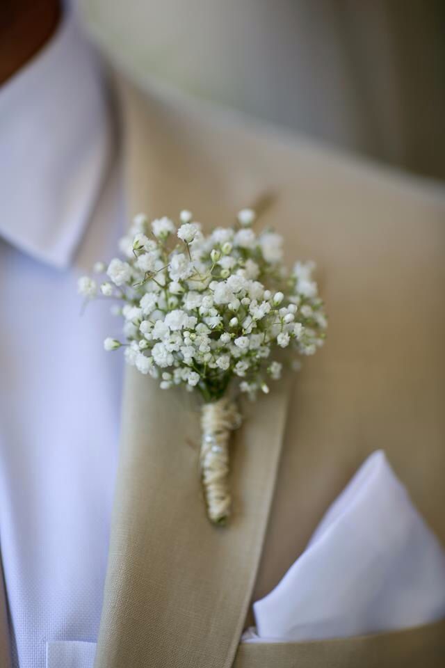 a boutonniere with baby's breath flowers on the lapel of a man