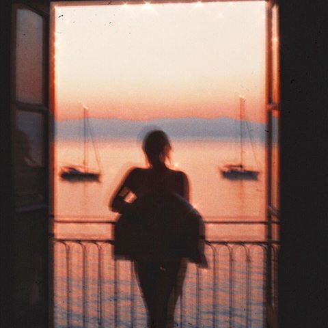 a woman standing in front of an open door looking out at boats on the water