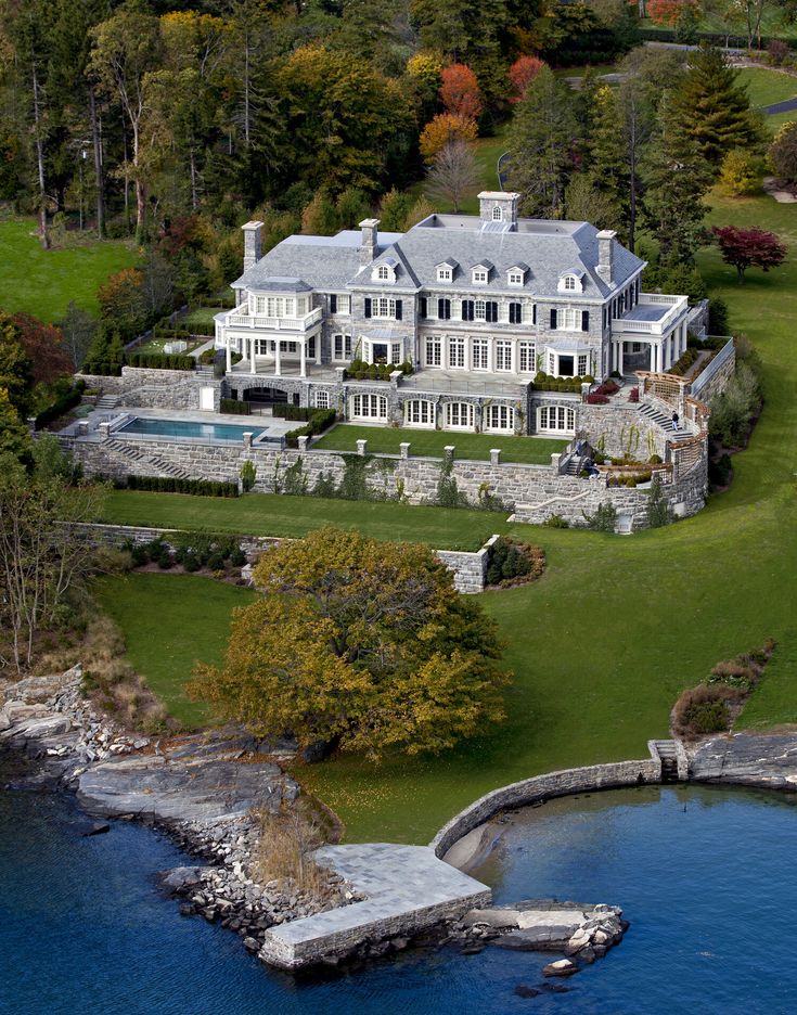 an aerial view of a large mansion with a pool in the foreground and trees surrounding it