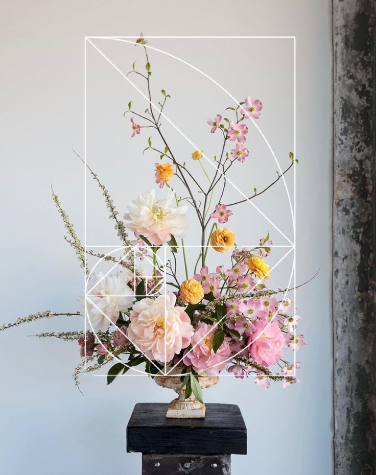 a vase filled with lots of flowers on top of a wooden table next to a wall