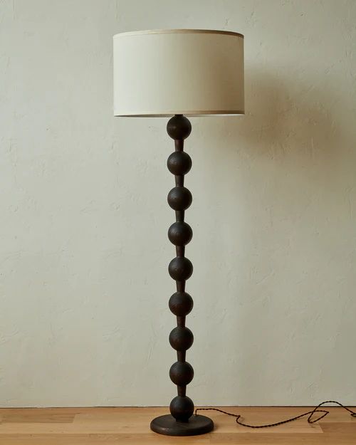 a lamp that is on top of a wooden table next to a wall and floor
