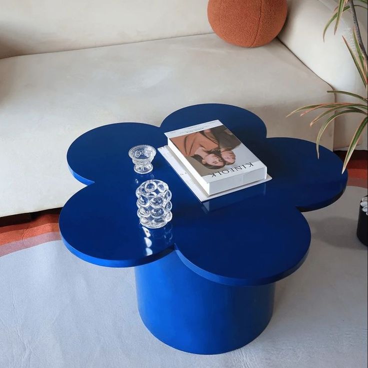 a blue coffee table sitting on top of a white couch next to a vase and candle
