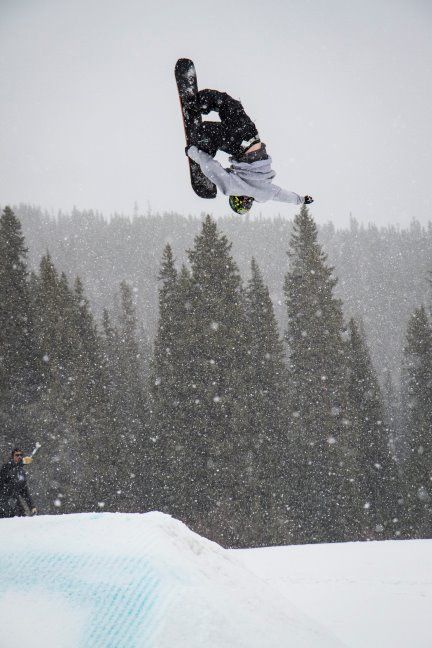 a man flying through the air while riding a snowboard in front of some trees