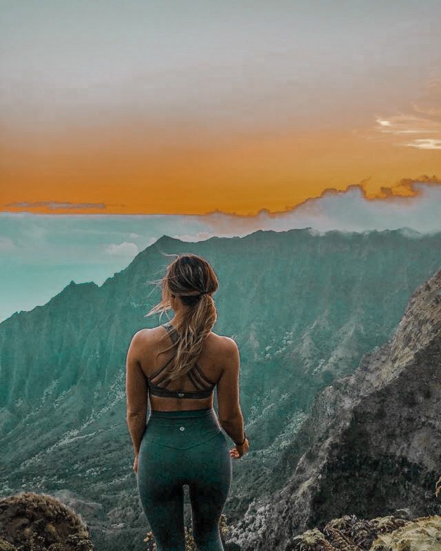 a woman standing on top of a mountain with her back to the camera