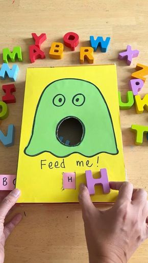 a child's hands holding up letters to spell out the word feed me with an image of a green monster