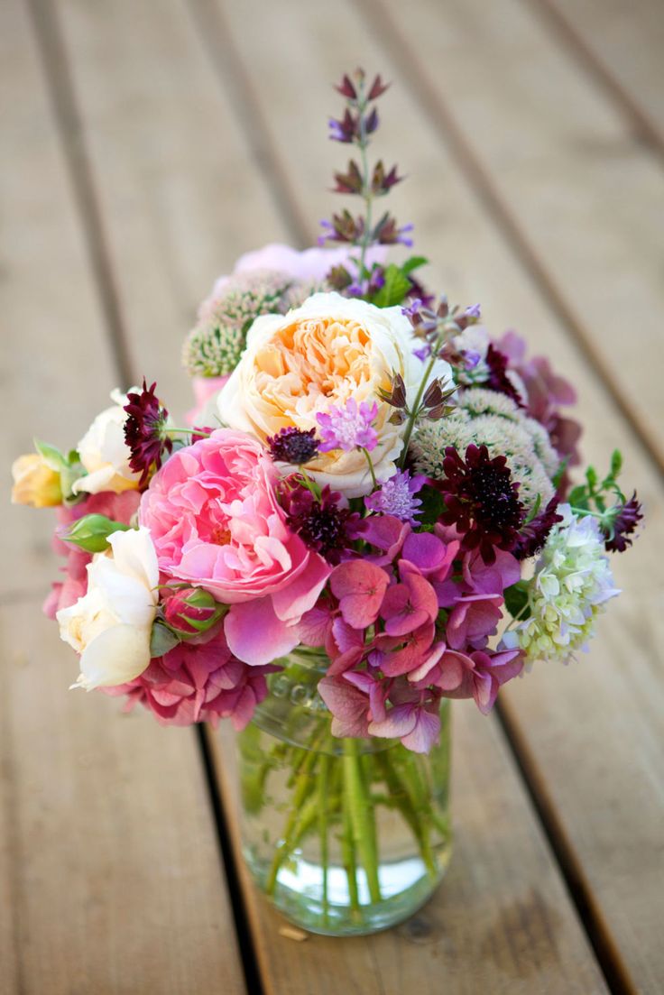 a vase filled with lots of flowers on top of a wooden table