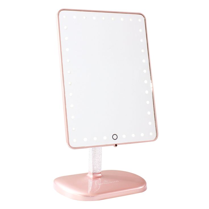 a pink vanity mirror with lights on it's sides and a small stand underneath the mirror