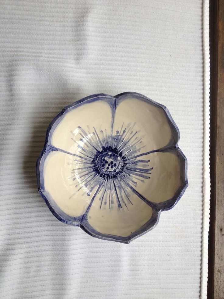 a blue and white flower shaped bowl on a tablecloth with a wooden frame in the background