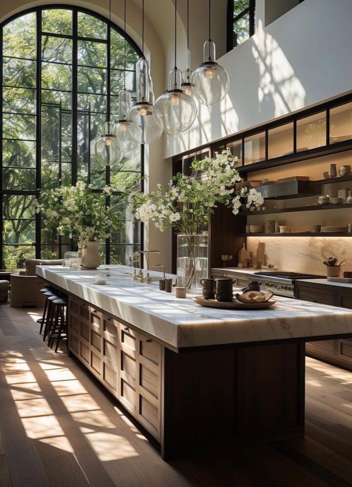 a kitchen with large windows and lots of counter space in front of the window are vases filled with flowers