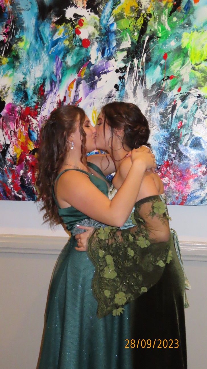 two women are hugging each other in front of a painting