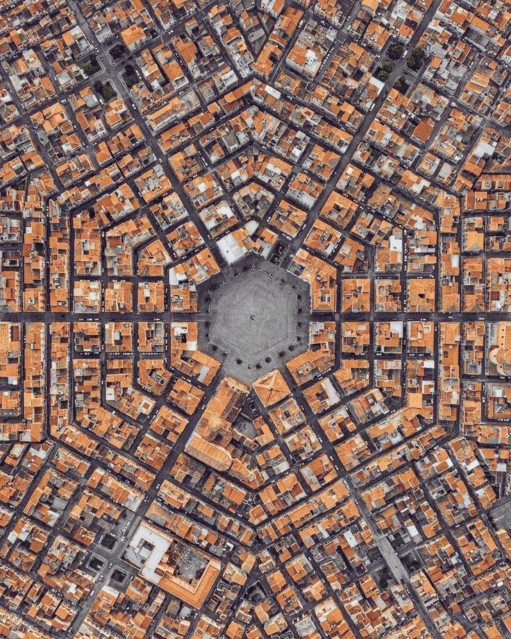 an aerial view of a city with lots of orange buildings on the sides and a black square in the middle