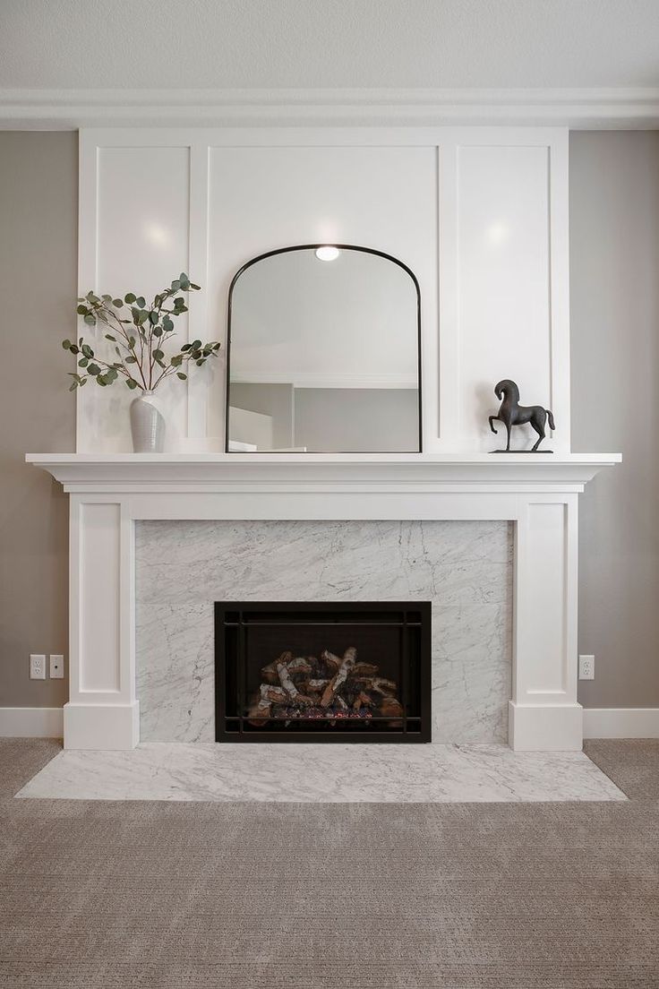 a white fireplace with a mirror above it