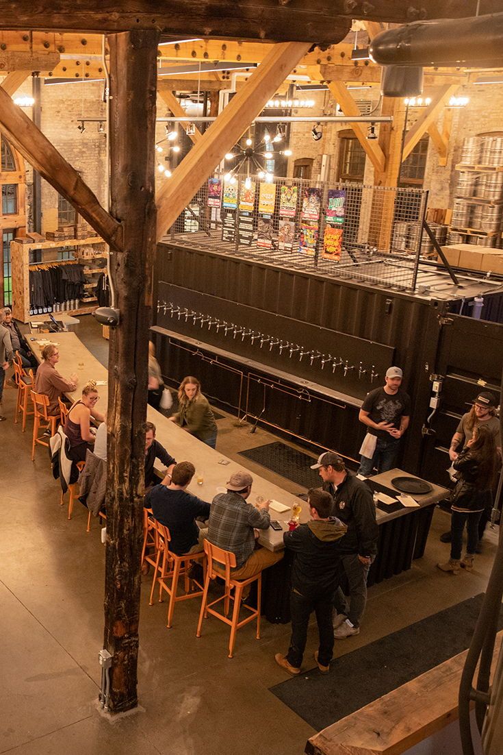people are sitting at tables in a large room with wooden beams and exposed ceilinging