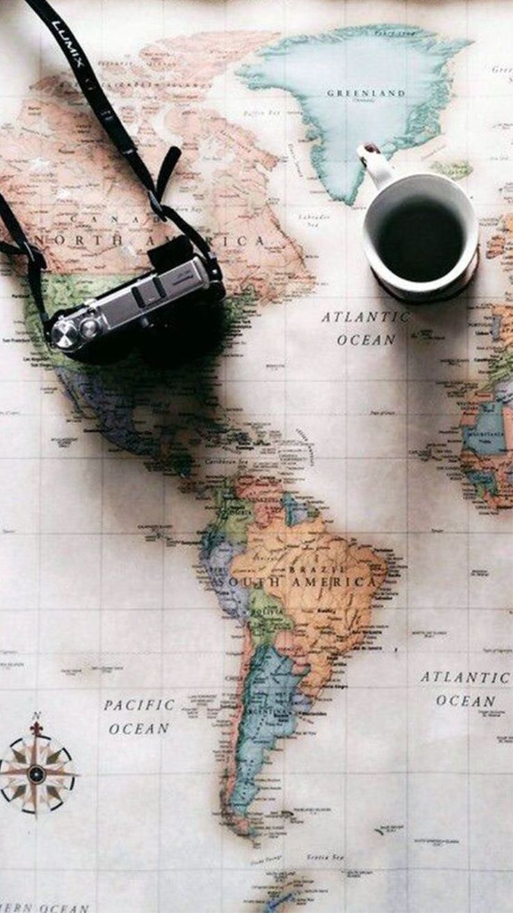 a map with a camera and a cup of coffee sitting on the table next to it